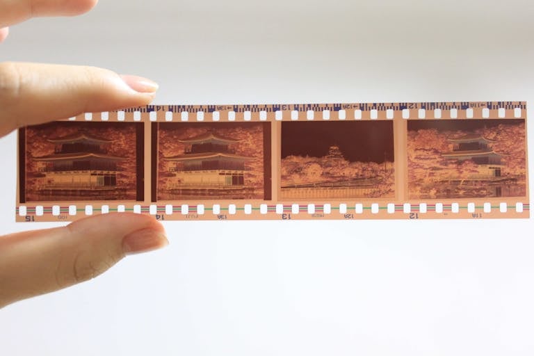 Detailed close-up photo of a film negative strip held by a person's hand, showcasing traditional photography.